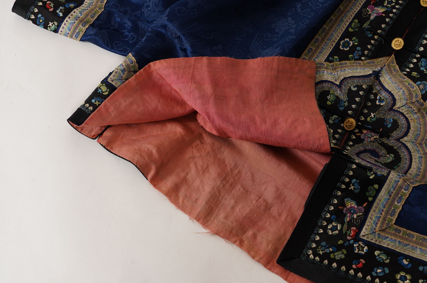 A late 19th century Chinese blue silk damask jacket, woven with Phoenix and auspicious symbols. The jacket edged with ornate rows of braiding and silk embroidery, the interior with original pink silk lining. The jacket f